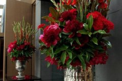 Red floral arrangements featuring vibrant red roses and greenery in elegant silver vases, showcasing wedding decor inspiration by Antaeus Flowers.
